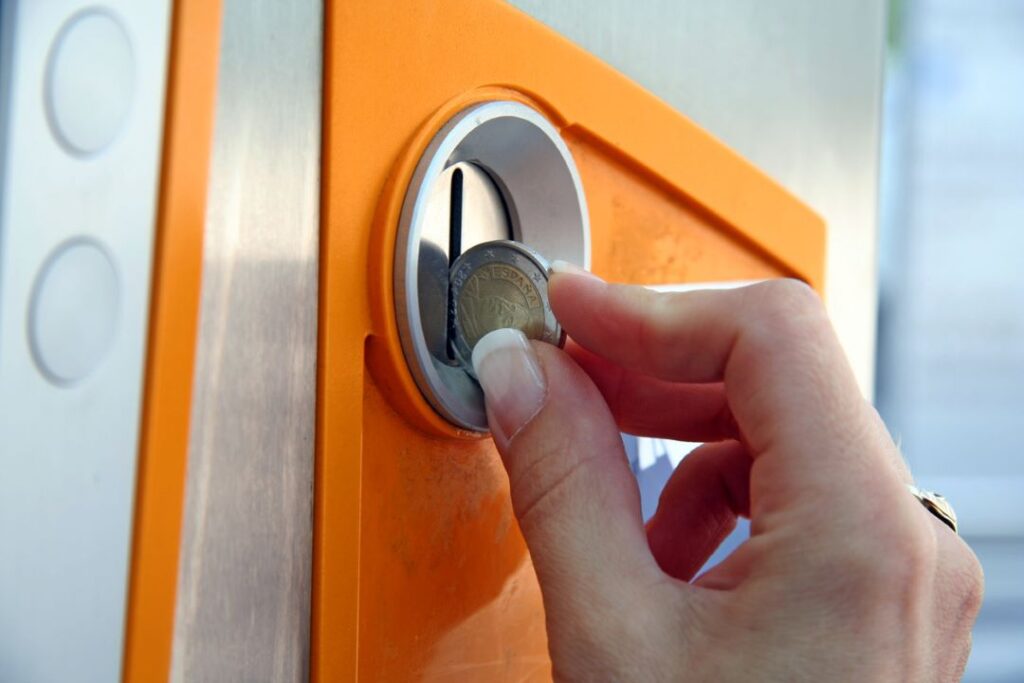 Hand putting coin in parking machine